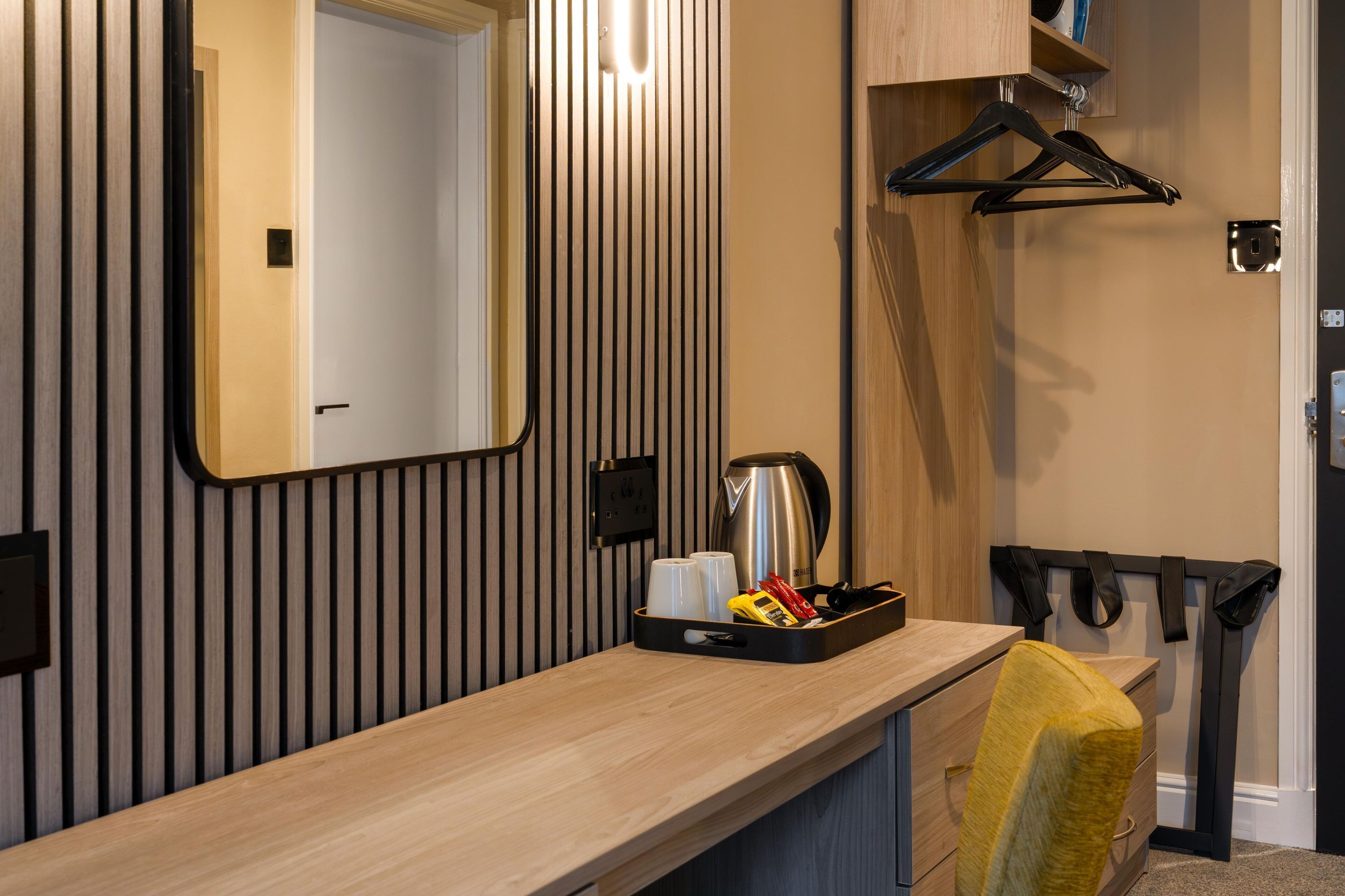 Un baño moderno con tocador de madera, un espejo, toallero y una bandeja con artículos de aseo.