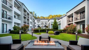 A courtyard with a fire pit, outdoor seating, and modern apartment buildings.