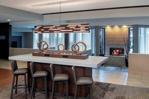 A modern kitchen with a central island, bar stools, a fireplace, and a contemporary pendant light. - Courtyard by Marriott Tarrytown Westchester County (Tarrytown)