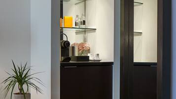 A modern bathroom with a glass shower enclosure, a potted plant, and a patterned floor.