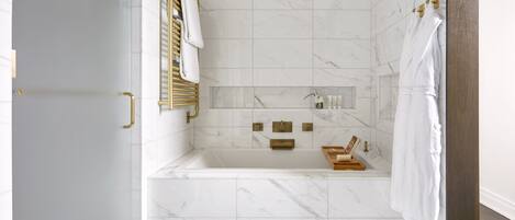 A modern bathroom with a marble floor, a freestanding bathtub, and gold fixtures.
