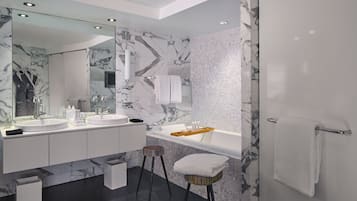 A modern bathroom with two sinks, a large mirror, and a bathtub.