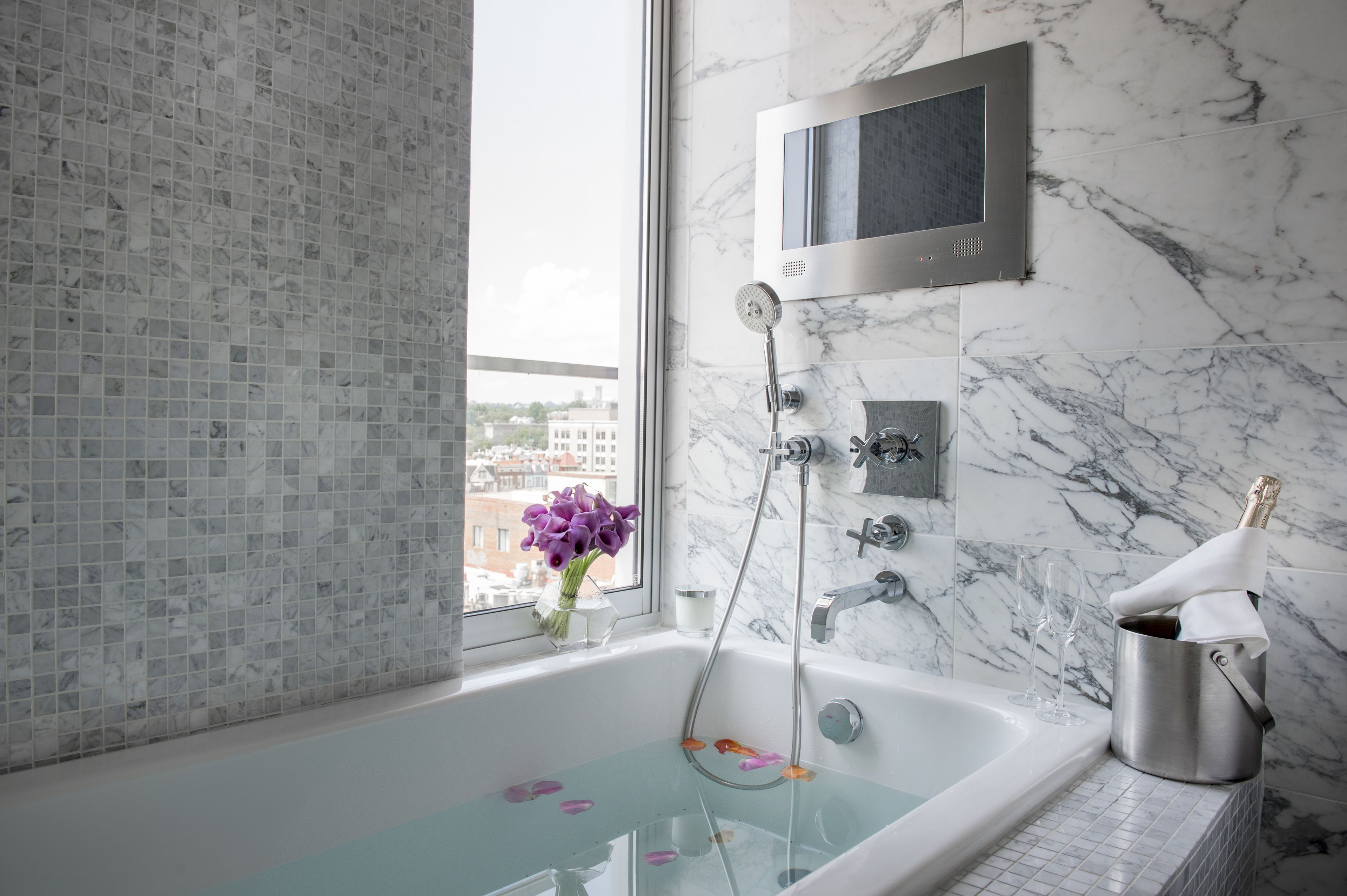 Un baño moderno con bañera, ducha y un ventanal grande.
