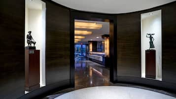 A modern lobby with a curved floor, dark wood paneling, and two sculptures on pedestals.