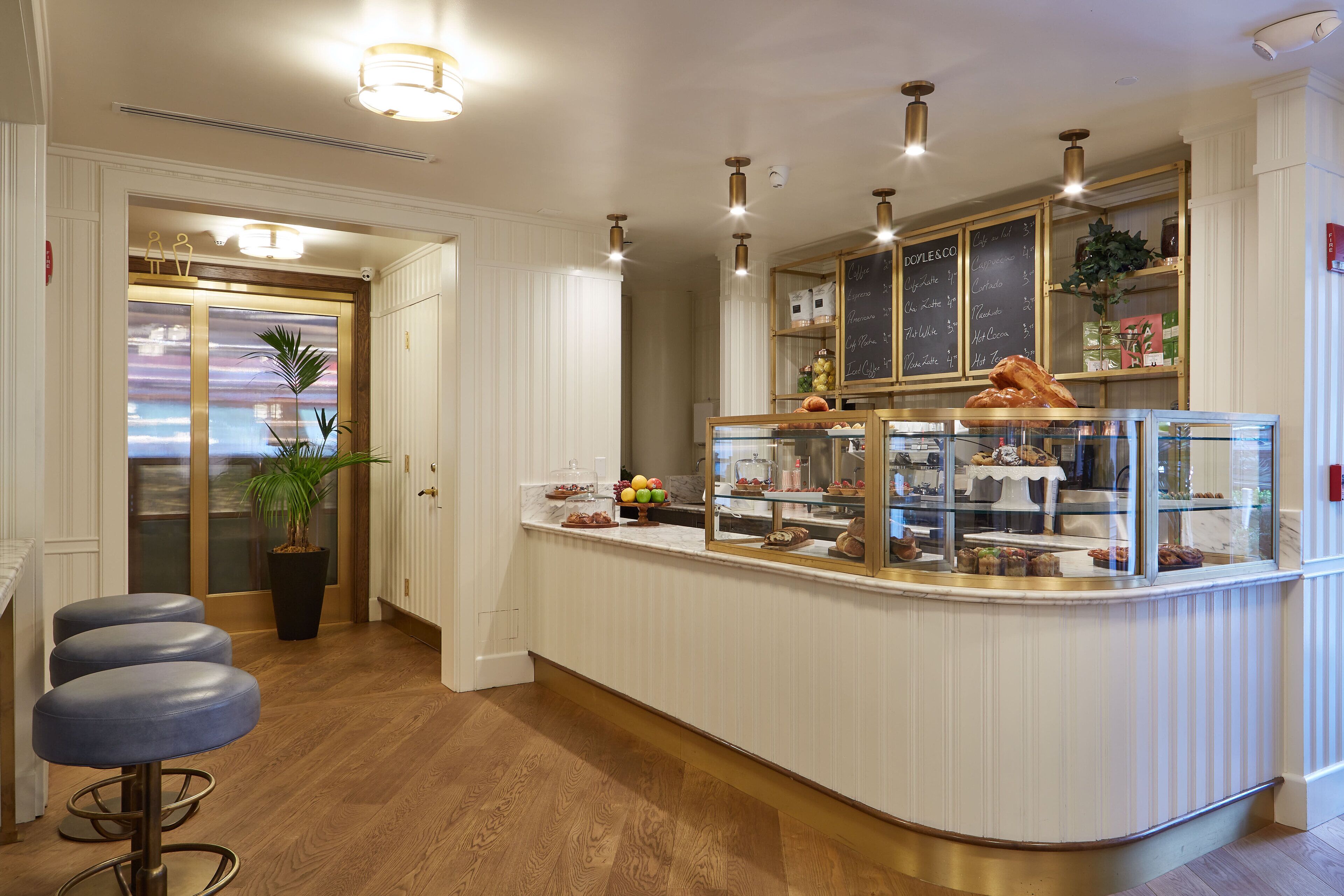 Una cocina moderna con una isla central, taburetes de bar y un menú en una pizarra.