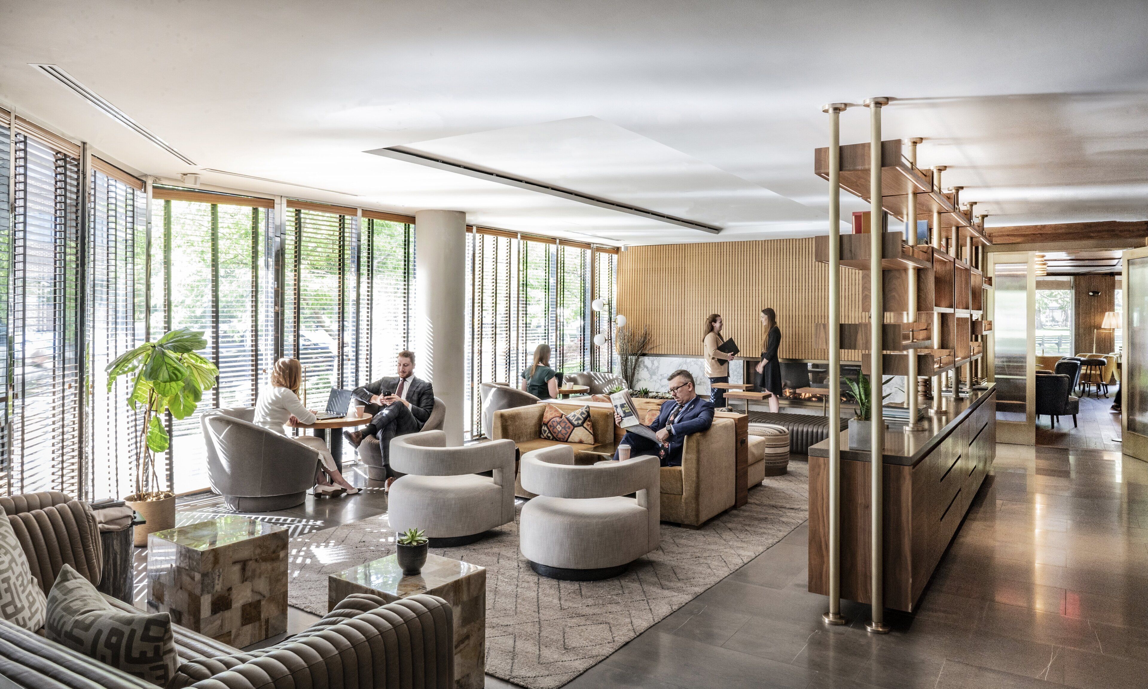 A spacious lobby with modern furniture, large windows, and a central seating area.