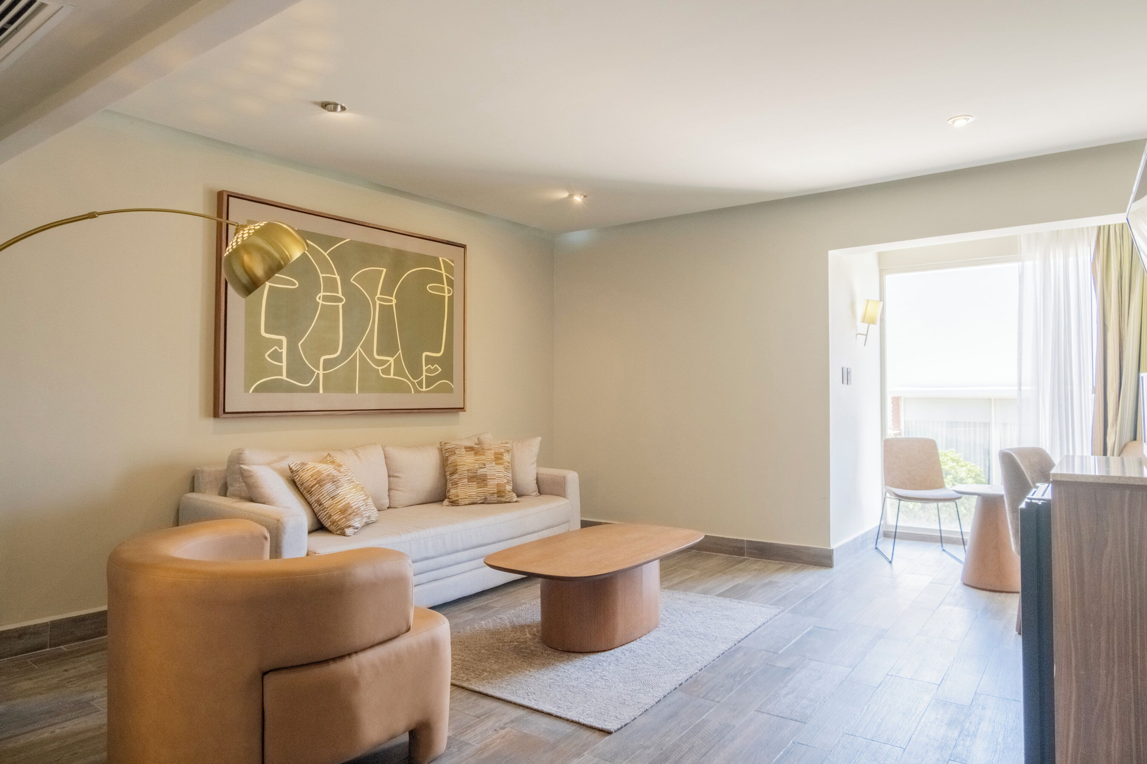 A modern living room with a sofa, armchairs, a coffee table, and a painting on the wall.