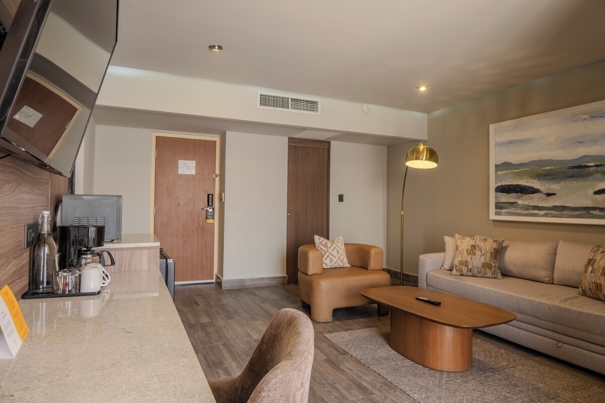 Een moderne woonkamer met een bank, salontafel en een schilderij aan de muur.