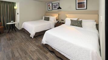 A hotel room with two beds, a small table, and a chair.