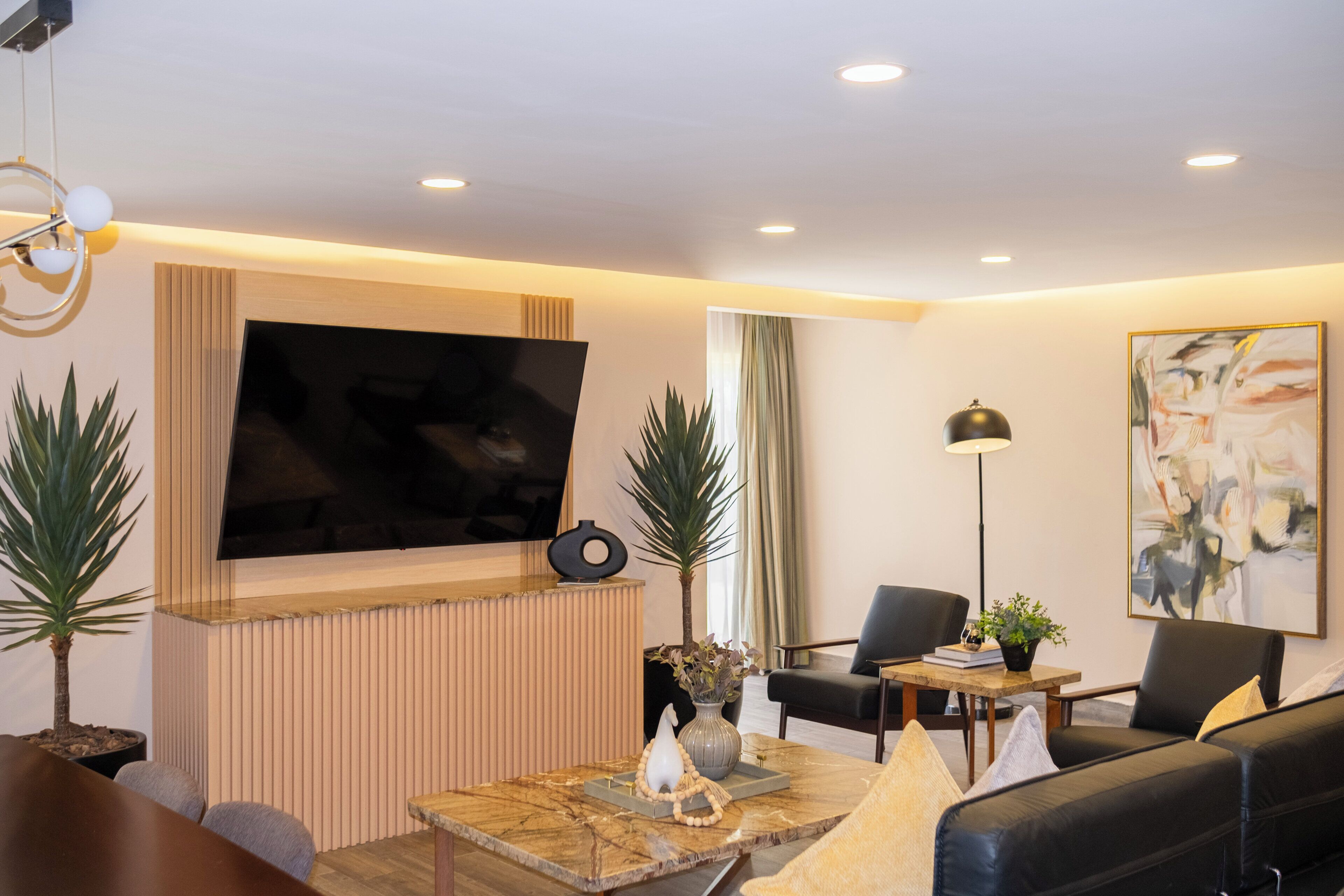 A modern living room with a flat-screen TV, a sofa, a coffee table, and a lamp.