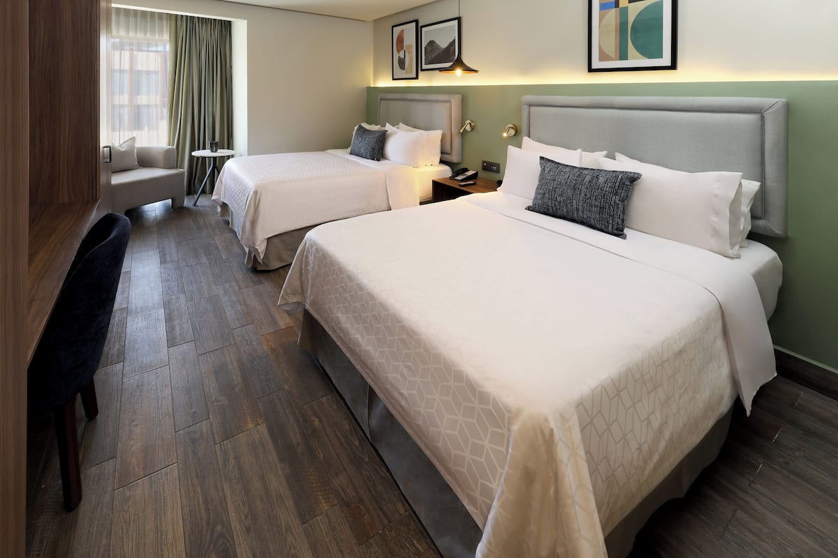 A hotel room with two beds, a desk, and a chair.