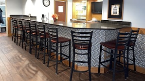 A modern kitchen with a bar area, wooden ceiling beams, and a tiled backsplash. - Howard Johnson by Wyndham Merrillville (Merrillville)