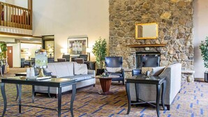 A spacious lobby with a stone fireplace, comfortable seating, and a patterned carpet. - Howard Johnson by Wyndham Merrillville (Merrillville)