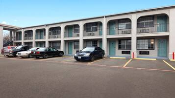 A multi-story motel with a row of parking spaces in front.