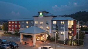 Un bâtiment de l’hôtel Holiday Inn Express doté d’une entrée centrale, d’un parking et d’un espace vert environnant.