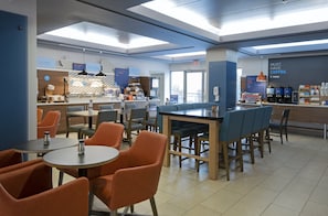 A modern cafe with seating arrangements, a coffee bar, and visible signage. - Holiday Inn Express Kamloops by IHG (Kamloops)