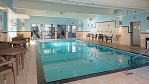A swimming pool with a tiled deck, lounge chairs, and a sunshade area. - Holiday Inn Express Kamloops by IHG (Kamloops)