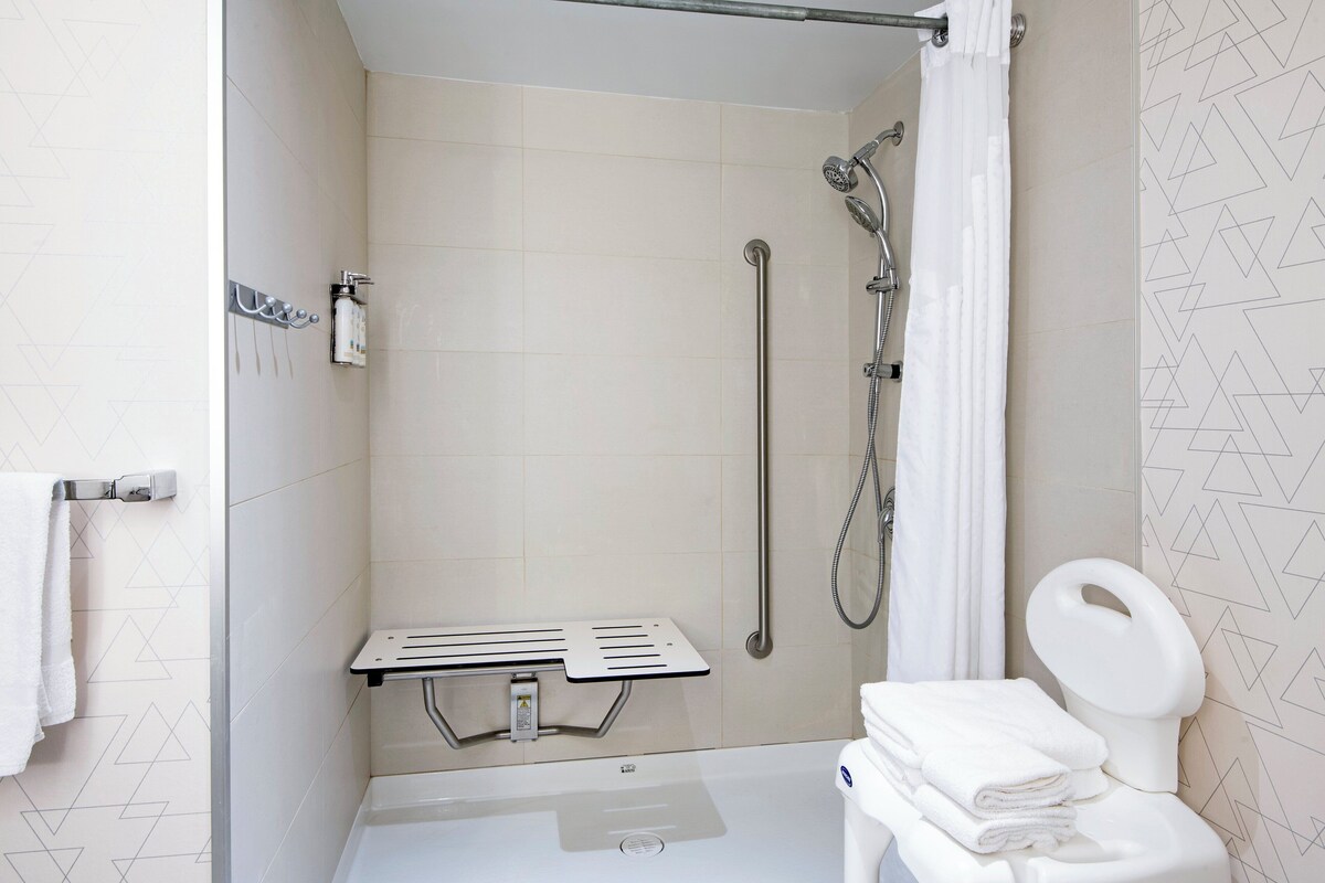 A modern bathroom with a shower, toilet, and a towel rack.