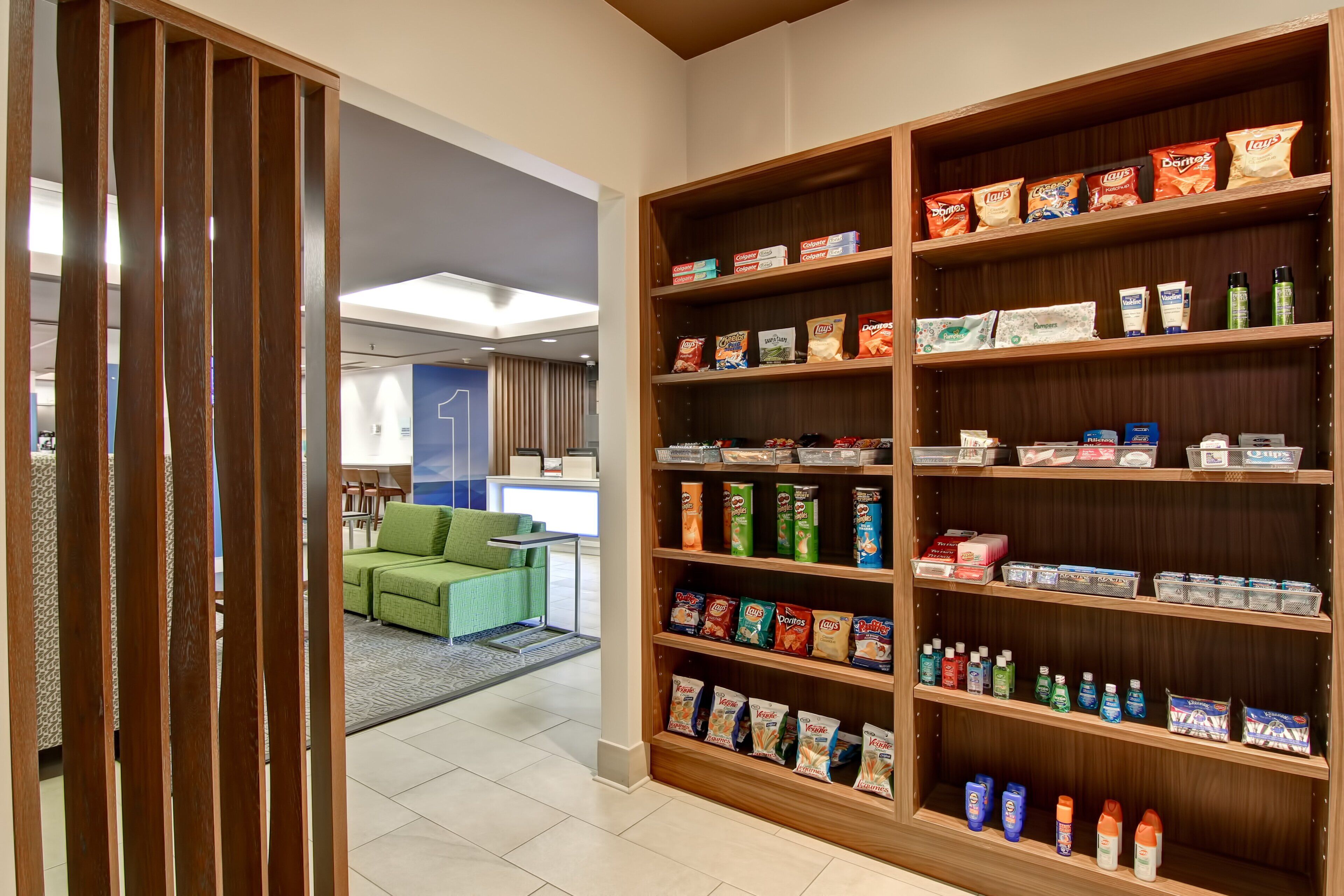 Eine Hotelhalle mit einem großen Bücherregal, gefüllt mit Snacks und Pflegeprodukten.