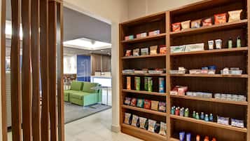 Eine Hotelhalle mit einem großen Bücherregal, gefüllt mit Snacks und Pflegeprodukten.