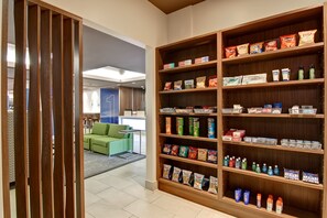 A hotel lobby with a large wooden bookshelf filled with snacks and toiletries. - Holiday Inn Express Kamloops by IHG (Kamloops)
