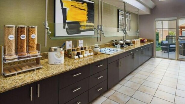 A modern kitchen with a granite countertop, dark cabinets, and a large window. - Residence Inn by Marriott Arlington (Arlington)