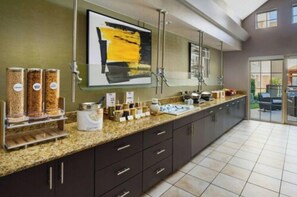 A modern kitchen with a granite countertop, dark cabinets, and a large window. - Residence Inn by Marriott Arlington (Arlington)