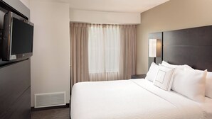 A hotel room with a large bed, a flat-screen TV mounted on the wall, and a window with curtains. - Residence Inn by Marriott Arlington (Arlington)