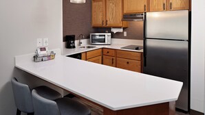 A modern kitchen with wooden cabinets, a stainless steel refrigerator, a microwave, and a white countertop. - Residence Inn by Marriott Arlington (Arlington)
