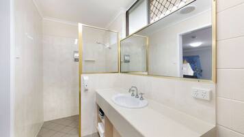 Un bany amb un lavabo blanc, un mirall i una dutxa.