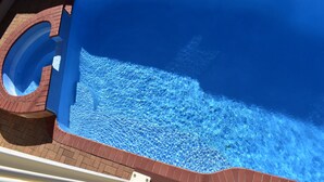 Una piscina con agua azul cristalina, rodeada por un patio de ladrillo.