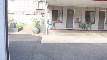 A hotel with a covered outdoor seating area, a fire extinguisher, and numbered doors.