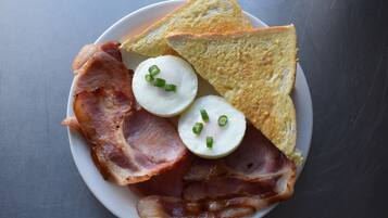 Un plato con tocino, huevos y tostadas.