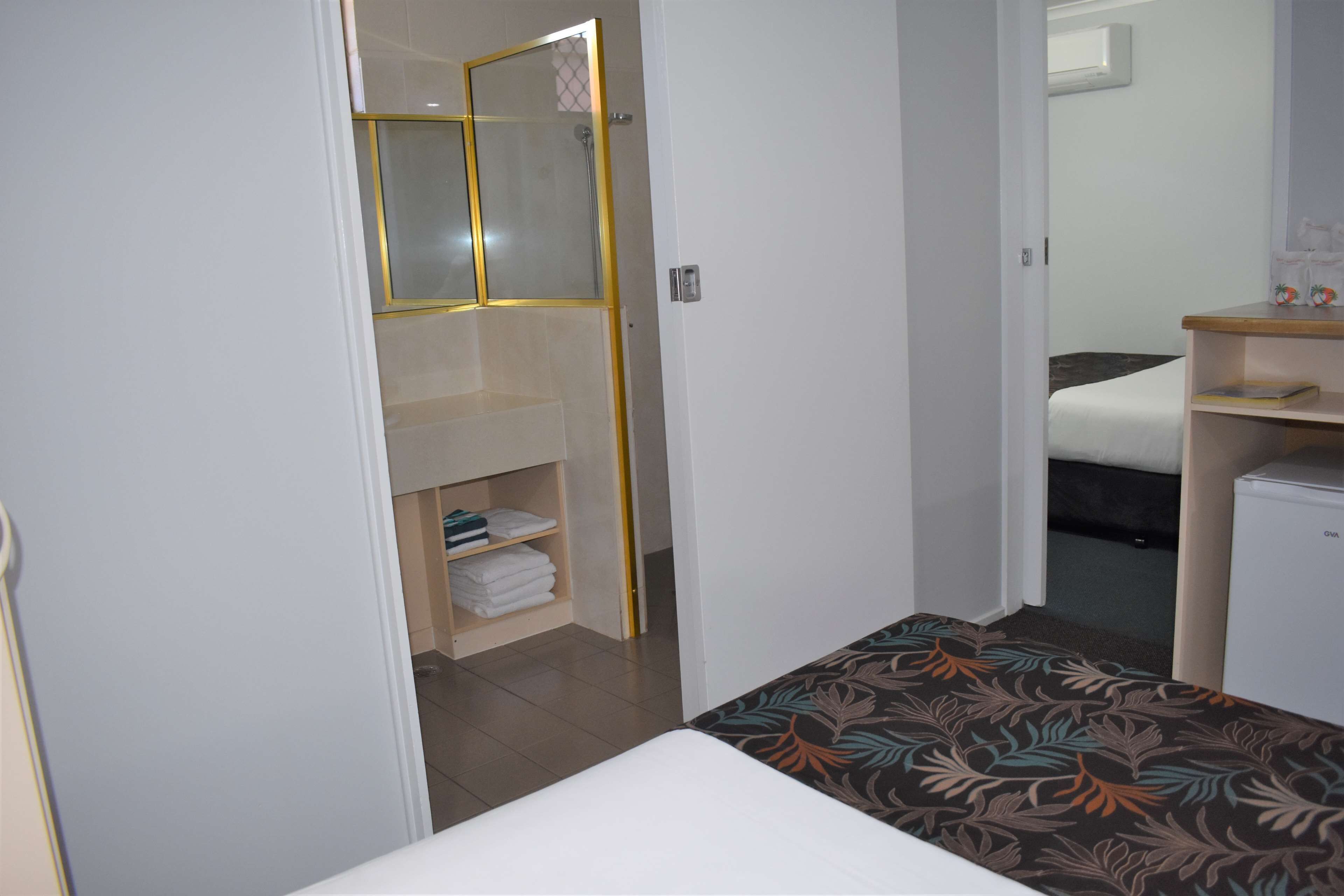 Quarto de hotel pequeno com cama, uma mesinha de cabeceira, guarda-roupa e zona de duche.