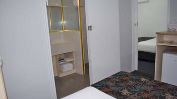Quarto de hotel pequeno com cama, uma mesinha de cabeceira, guarda-roupa e zona de duche.