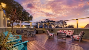 A wooden deck with outdoor furniture and a sunset view.