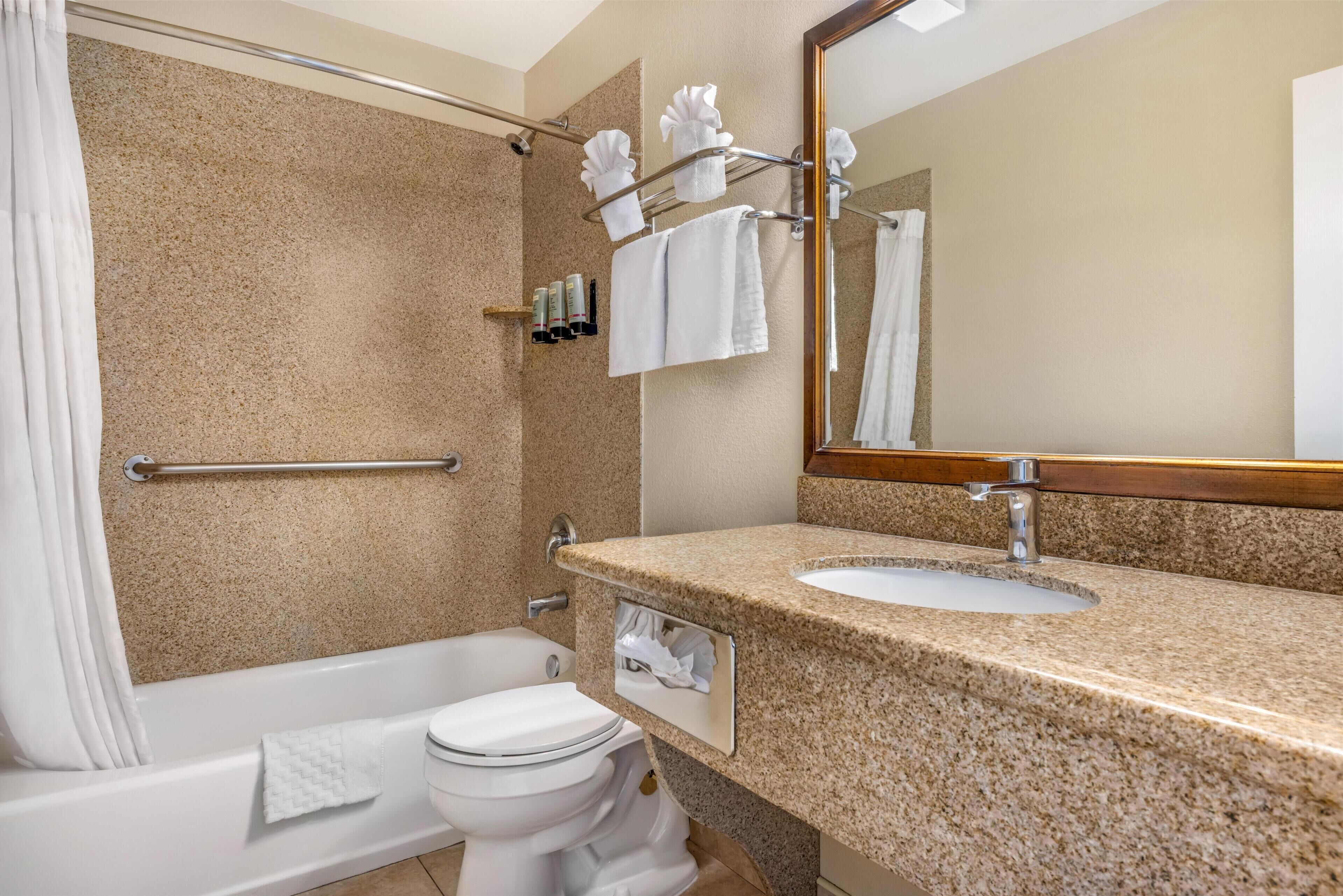 A bathroom with a bathtub, toilet, sink, and a mirror.