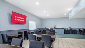 A conference room with tables and chairs, a kitchen area, and a TV displaying 'Free Wi-Fi All Rooms'. - Red Roof Inn Nacogdoches (Nacogdoches)