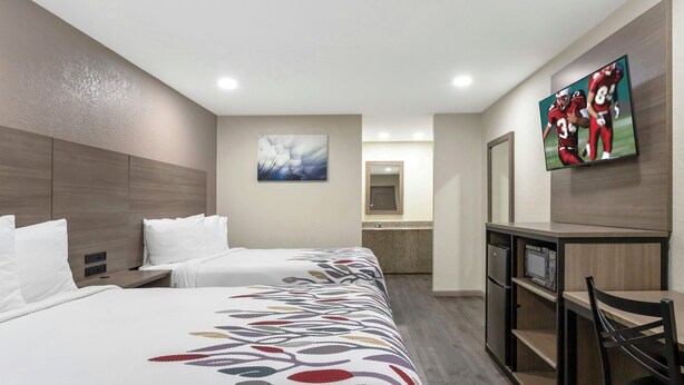 Habitación de hotel con dos camas, un escritorio, un televisor y un espejo.