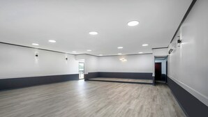 Una habitación amplia con suelo de madera, luces empotradas en el techo y una pared decorativa oscura.