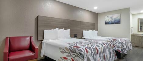 Ein Hotelzimmer mit einem Bett, einem roten Sessel und einem Kopfteil.