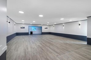 A spacious room with a wooden floor, recessed ceiling lights, and a blue accent wall with a logo. - Red Roof Inn Nacogdoches (Nacogdoches)
