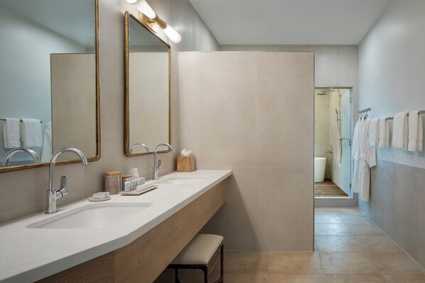 A modern bathroom with a double sink, large mirrors, and a shower area.