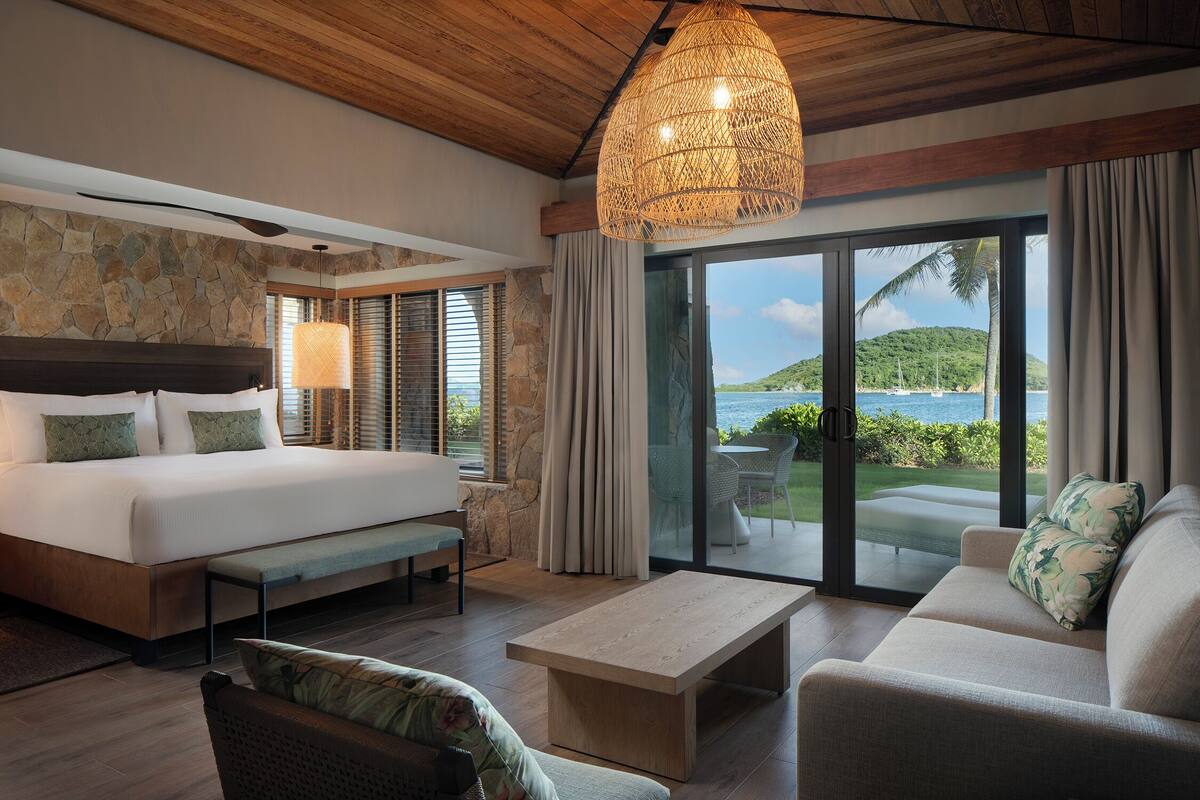 Une chambre avec un grand lit, un canapé, une table basse et une vue sur la mer.