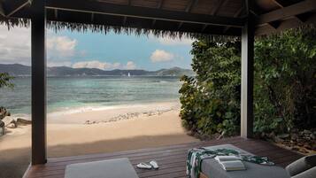 Un espacio de estar al aire libre techado con vista a una playa y al mar.