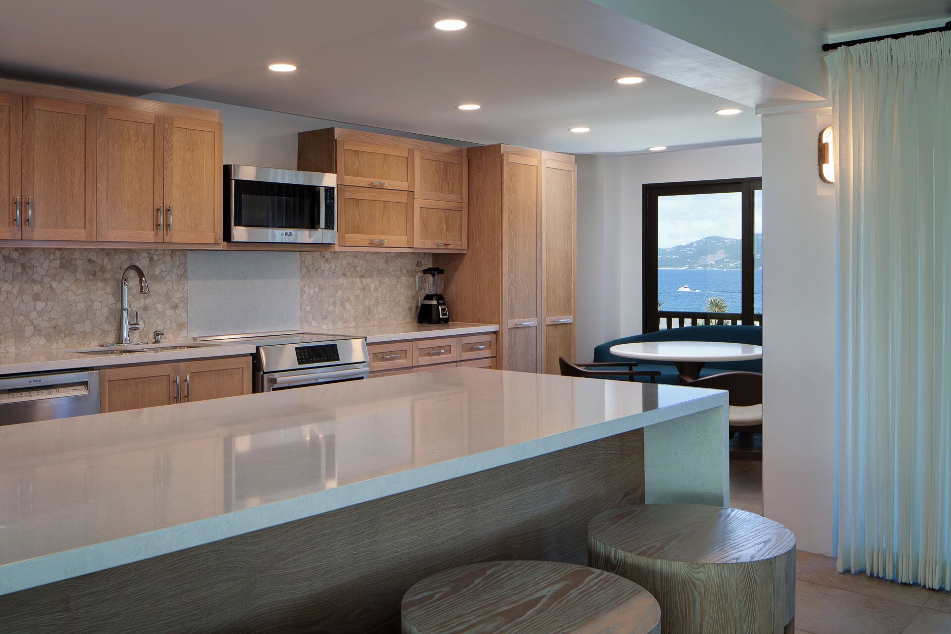 A modern kitchen with wooden cabinets, stainless steel appliances, and a large island with stools.