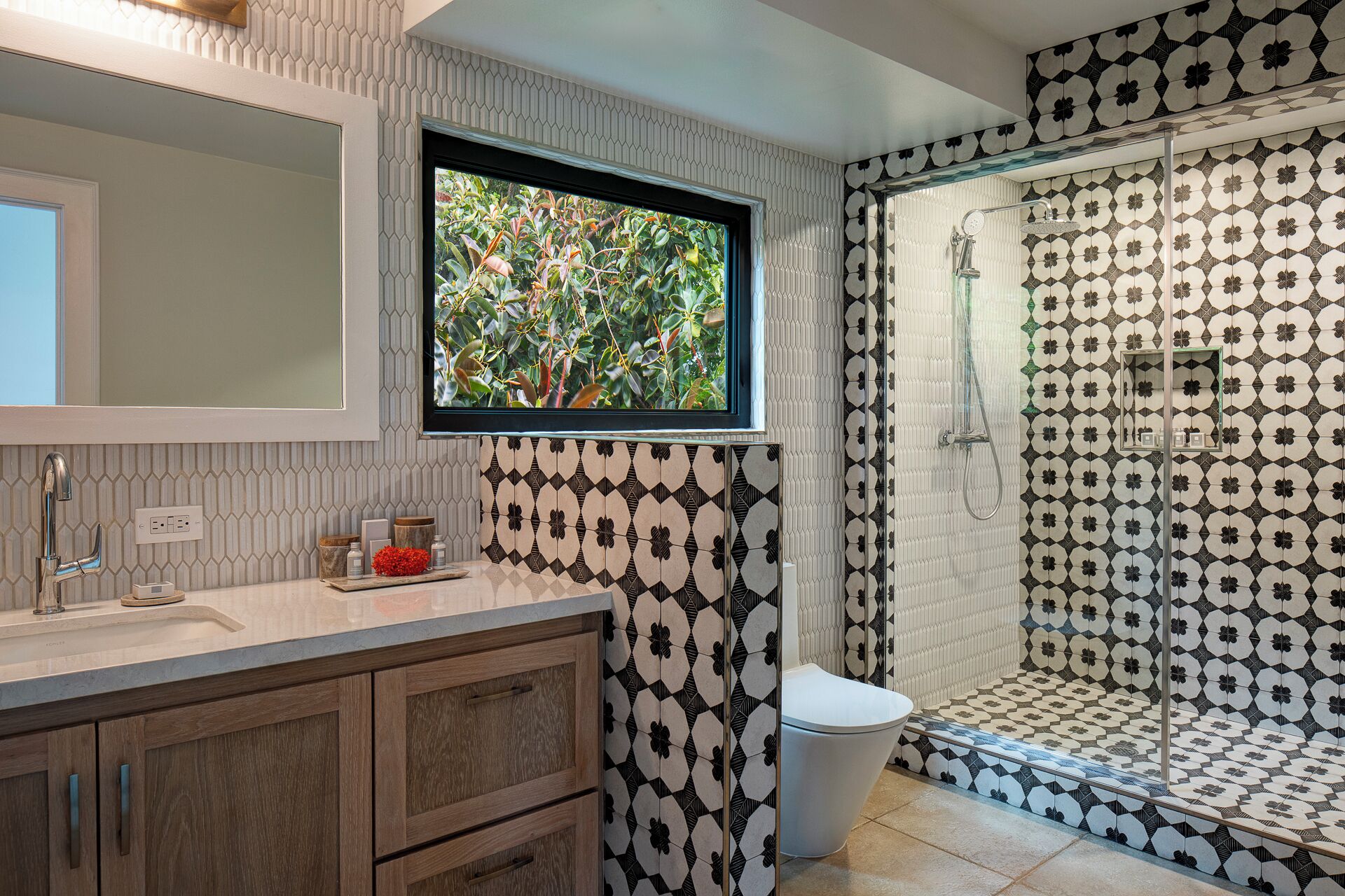 Ein Badezimmer mit Dusche, Waschbecken mit Spiegel und Fenster mit Blick auf Grünflächen.