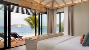 A bedroom with a large bed, a view of the sea, and a balcony with chairs. - Peter Island Resort (Sprat Bay)