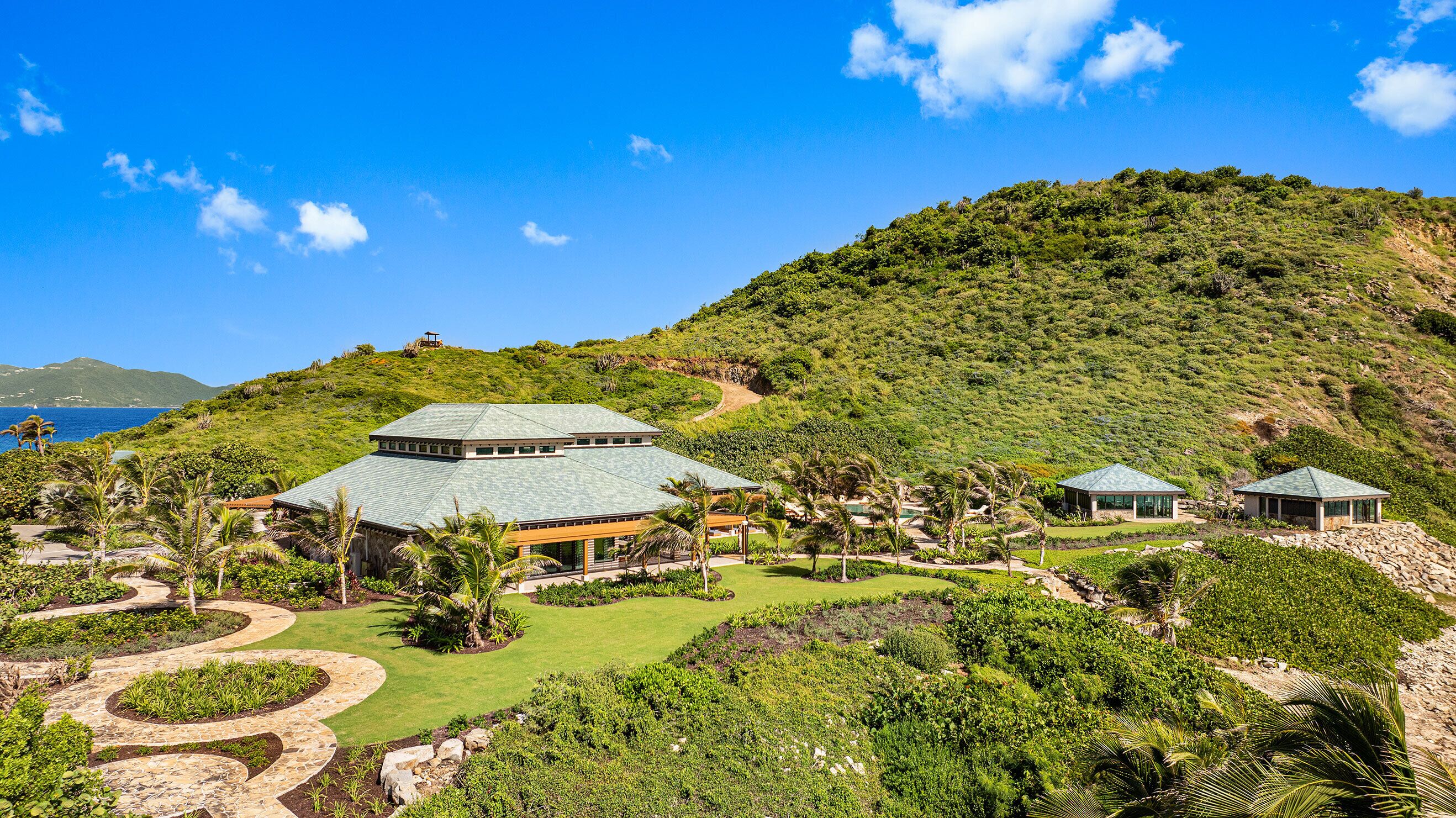 Un resort con un edificio grande, estructuras más pequeñas y un jardín bien cuidado con un sendero sinuoso.