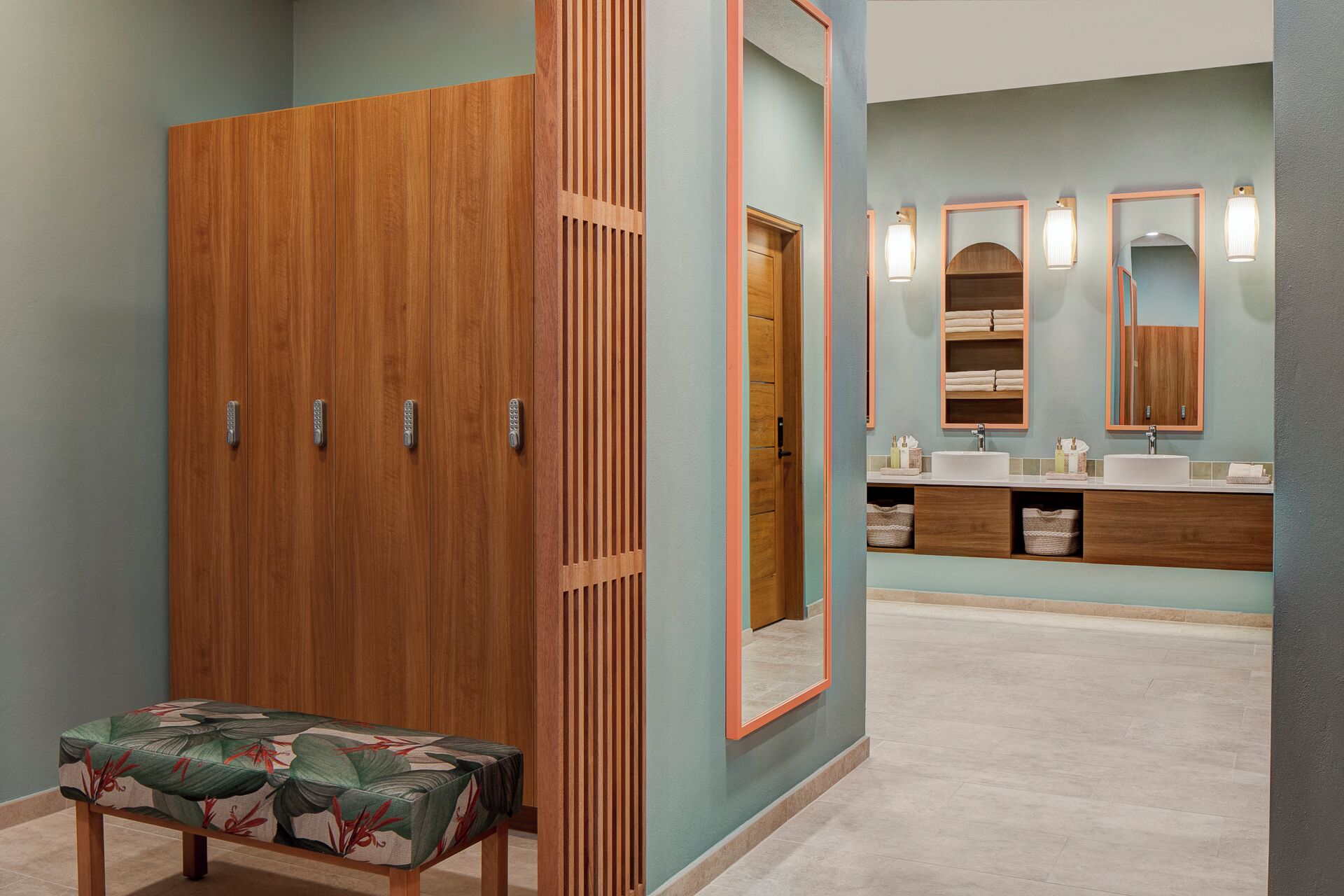 Een badkamer met een houten garderobe, een bankje en een wastafelmeubel met spiegels en planken.